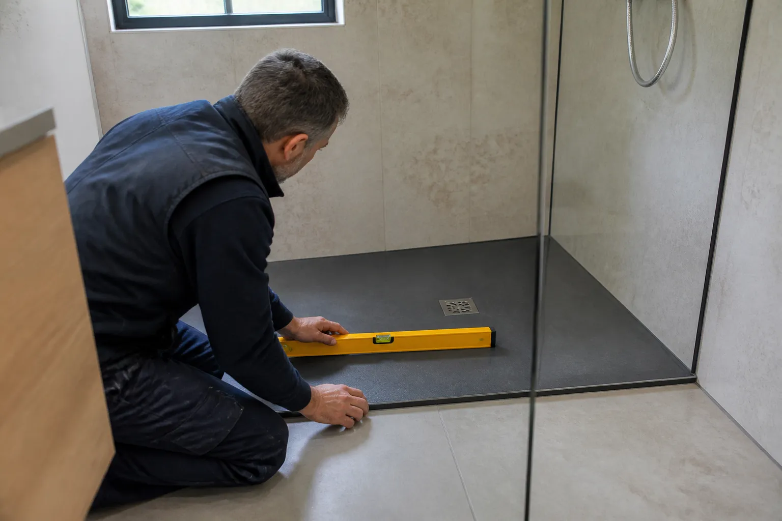 Expert verifiant la pente d une douche a l italienne dans une salle de bains renovee a Nantes